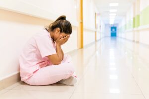 A cancer registrar professional sitting in a hospital hallway dealing with healthcare staffing shortages