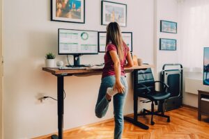 Picture of an MRA Cancer Registrar working from home and stretching her leg at a standing desk