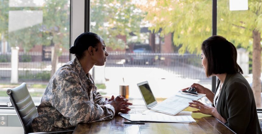 A military veteran consulting with a cancer registry professional in a healthcare office conference room